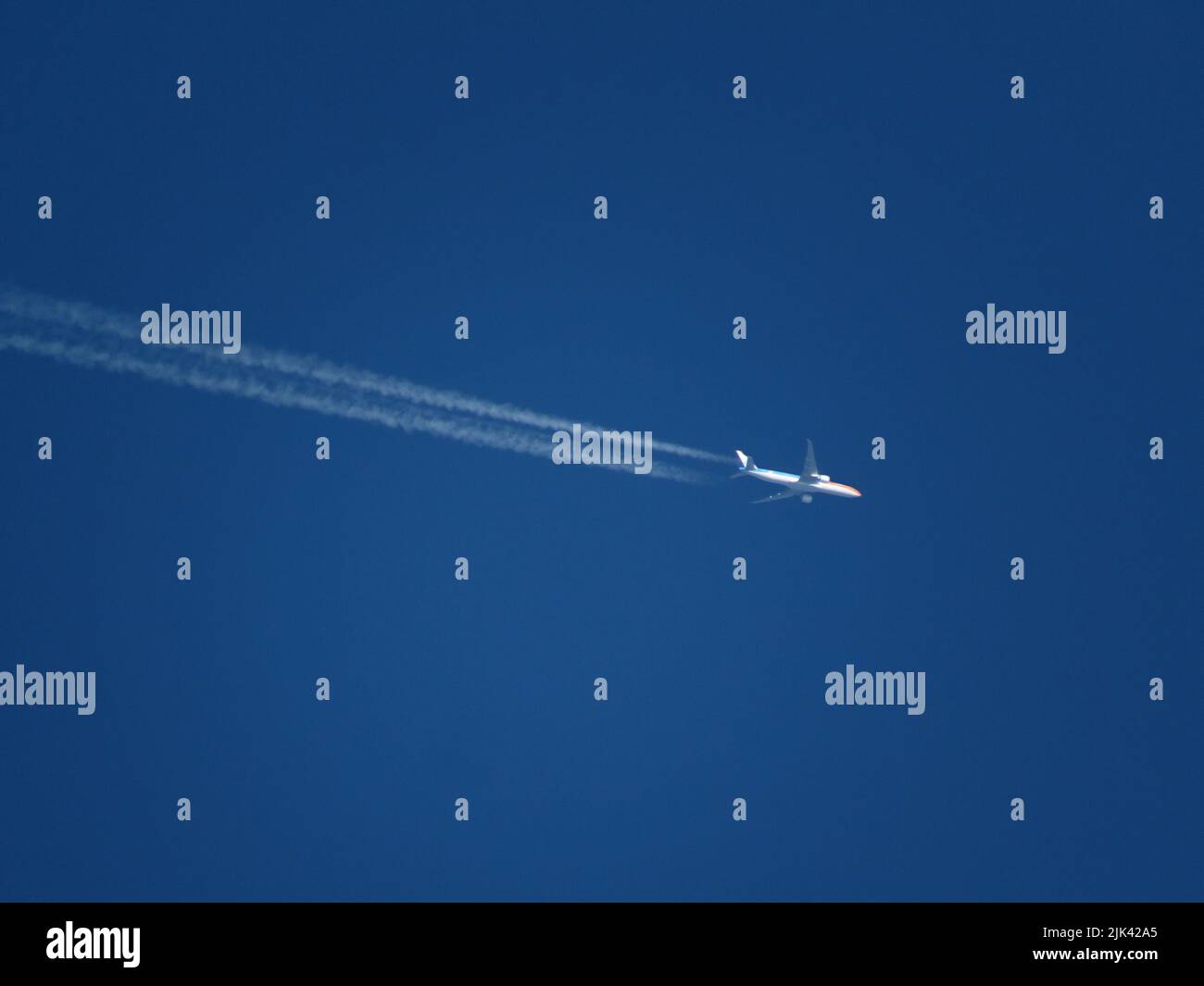 Telephoto view of a KLM Boeing 747 airliner with special livery flying at high altitude with contrails. Stock Photo