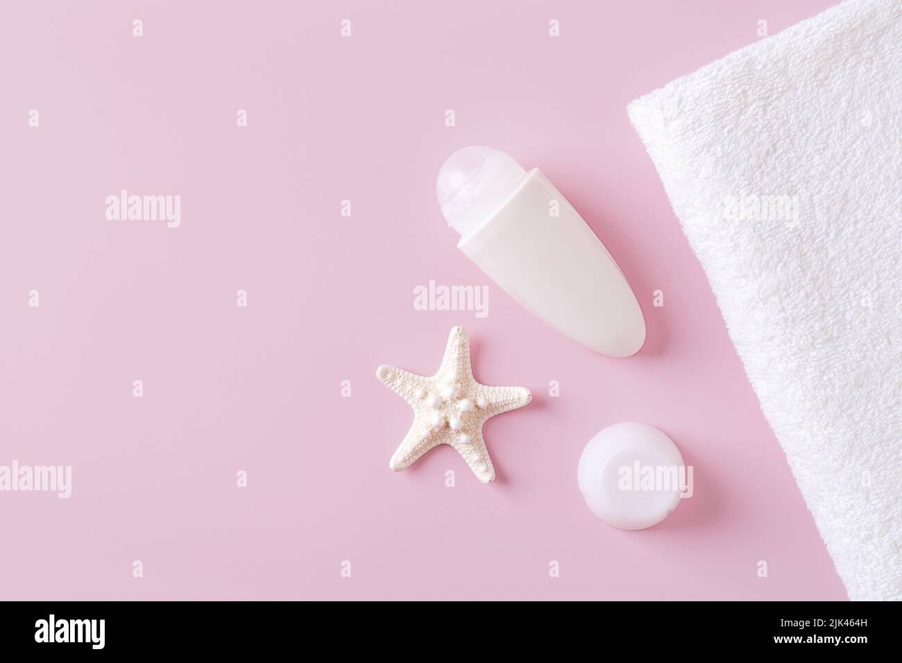Roll on antiperspirant deodorant, bath towel and sea star on a pastel pink background. Concept of body care, toiletries and natural cosmetics. Stock Photo