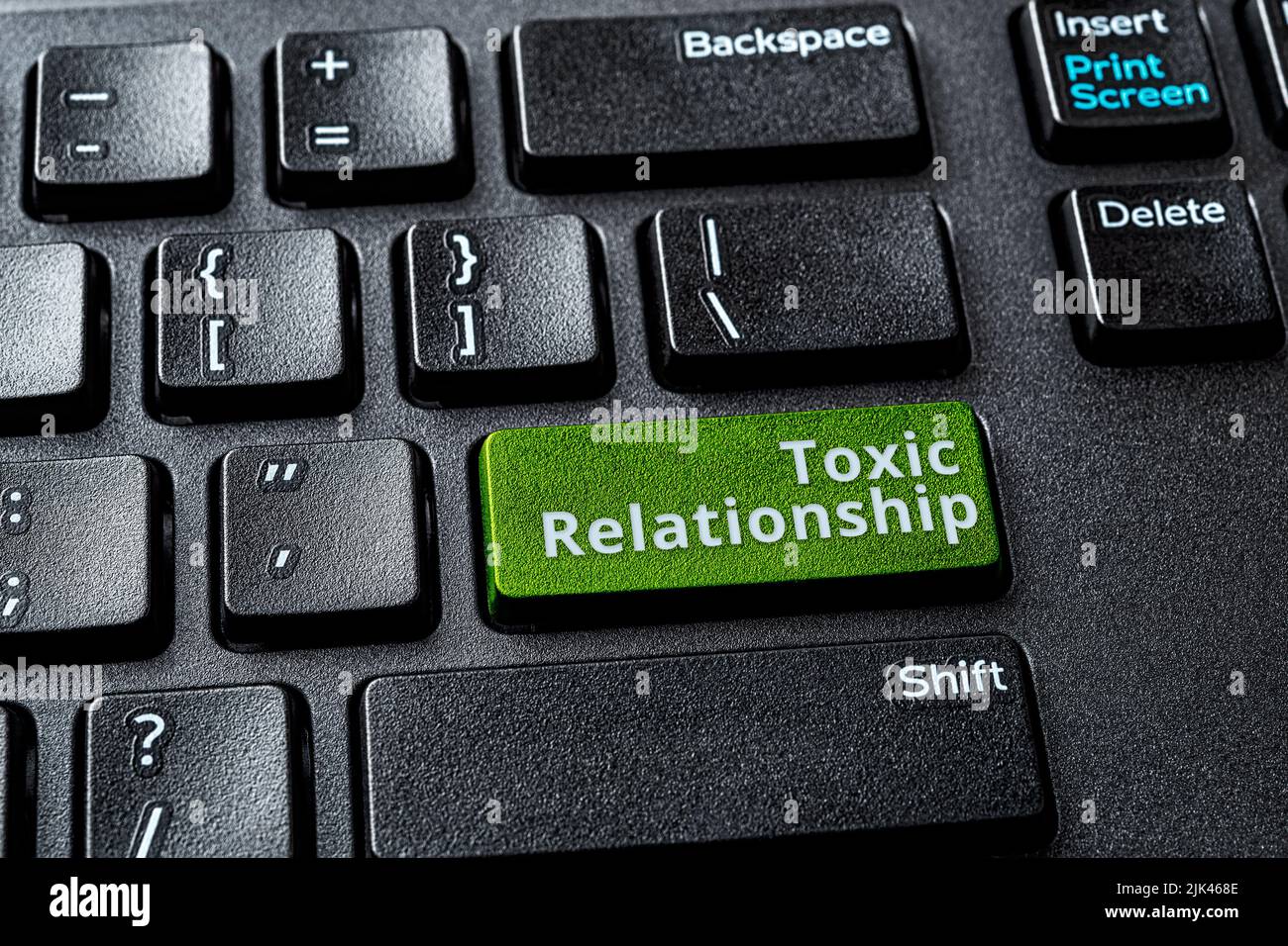 Toxic relationship words on the green enter key of a desktop computer keyboard. Concept of unsupported, misunderstood, demeaned relationship online. Stock Photo