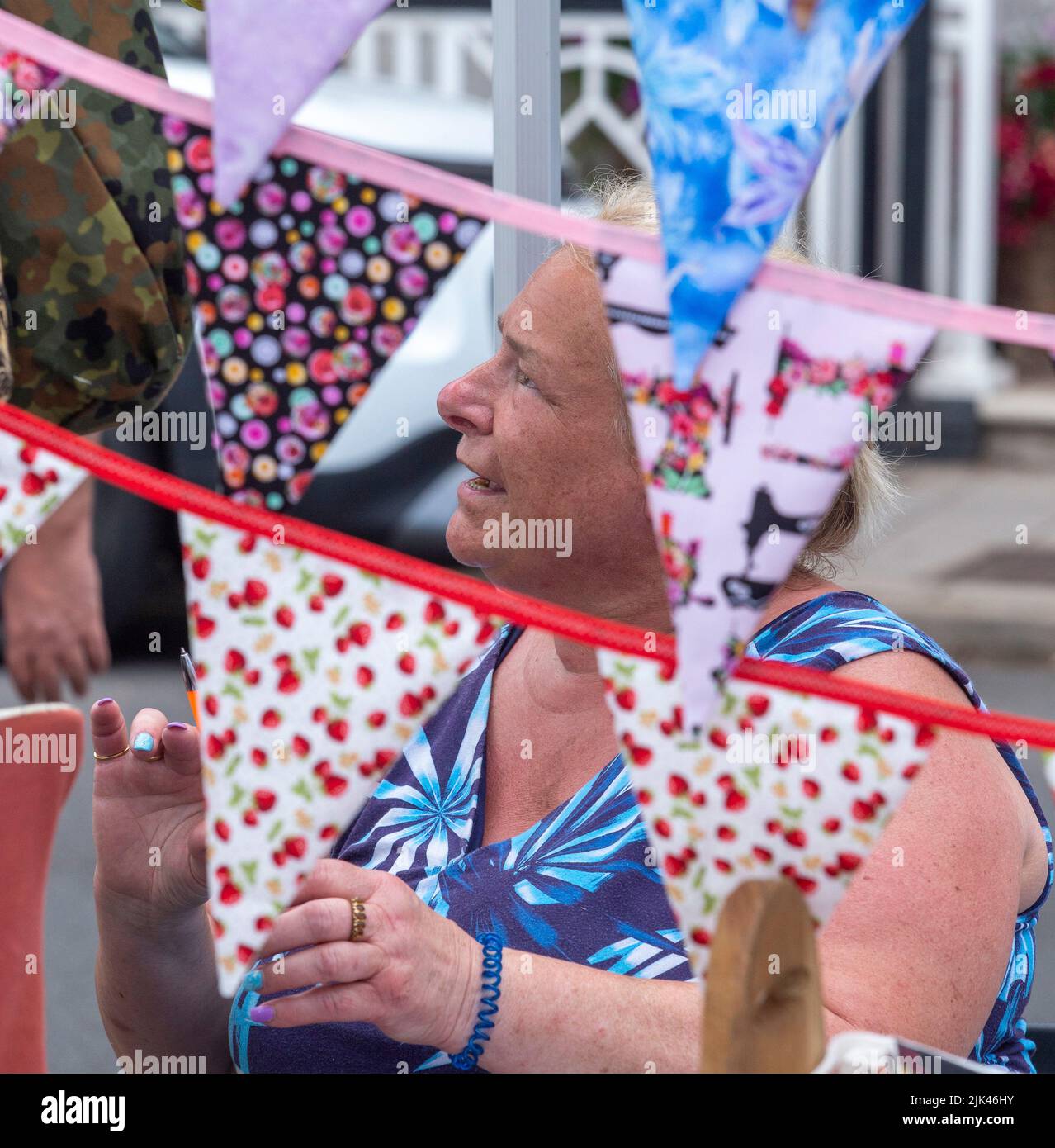 Sidmouth, 30th July 2022 Punting Bunting - a bunting seller brings colour to the seafront at Sidmouth as Folk Week gets under way. Tony Charnock/Alamy Live News Stock Photo