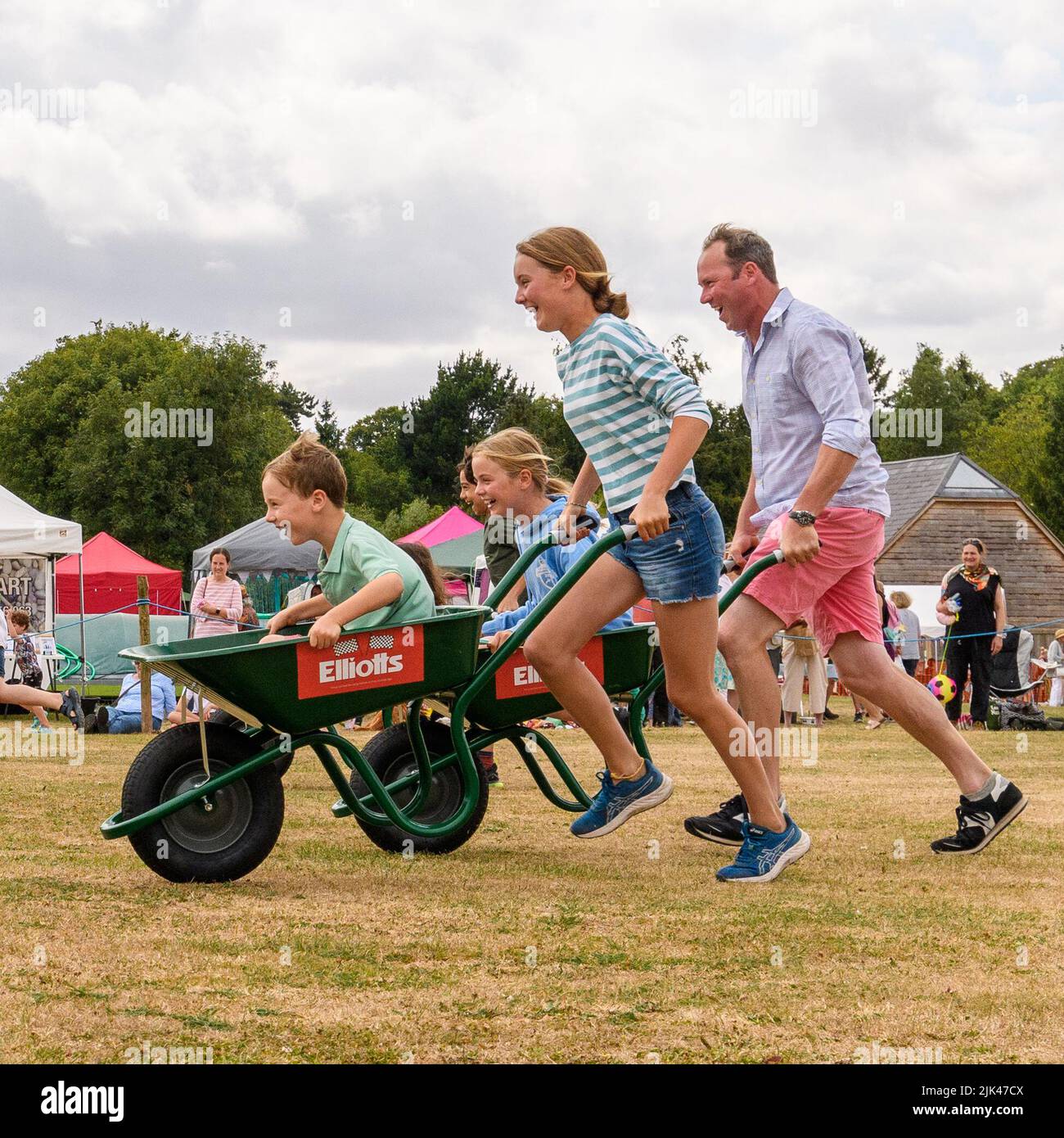 Damerham near Fordingbridge, Hampshire, UK, 30th July 2022. Family fun for competitors in the wheelbarrow racing at the Damerham Fair and Horticultural Show. Paul Biggins/Alamy Live News Stock Photo