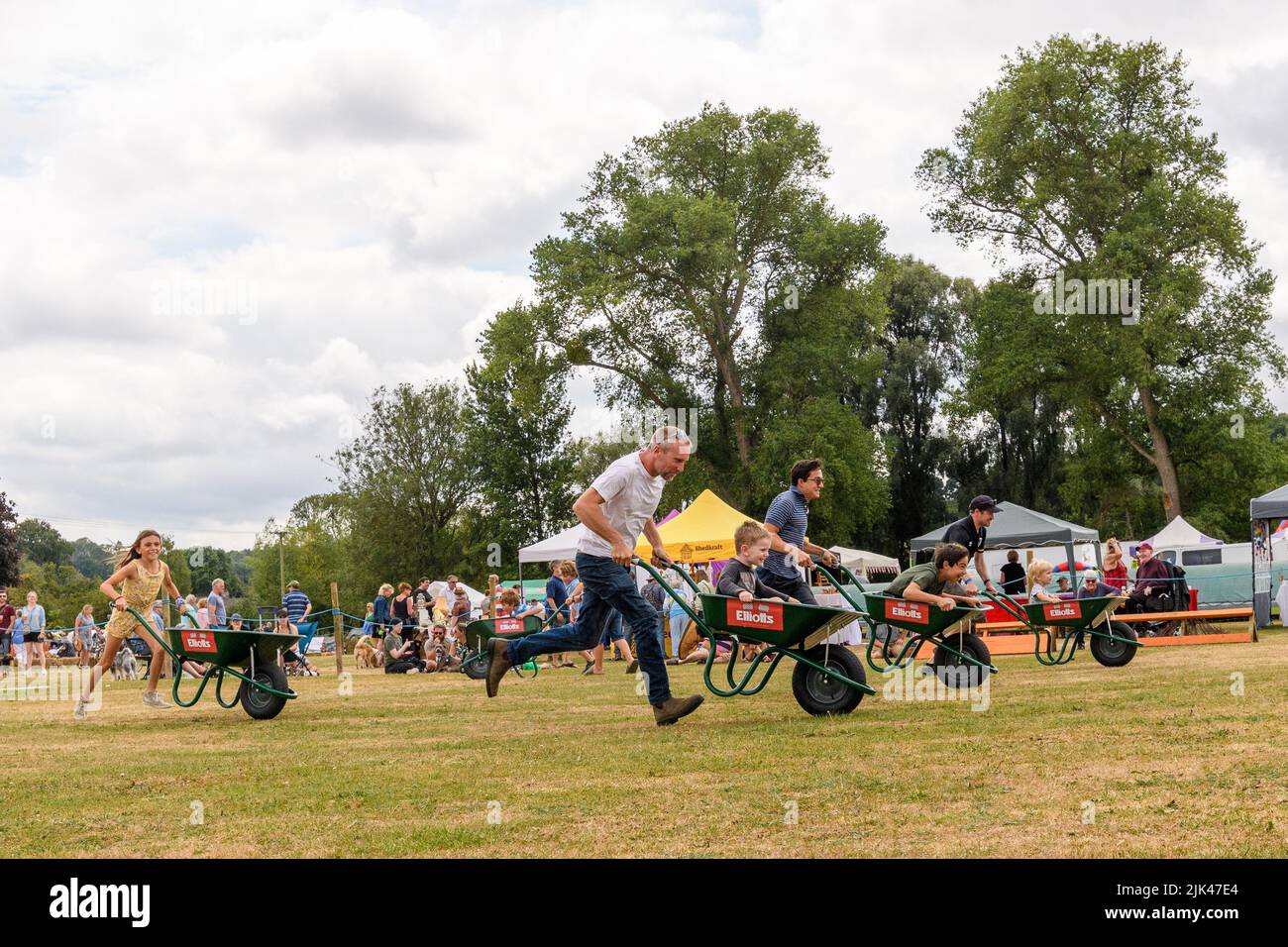 Damerham near Fordingbridge, Hampshire, UK, 30th July 2022. Family fun for competitors in the wheelbarrow racing at the Damerham Fair and Horticultural Show. Paul Biggins/Alamy Live News Stock Photo