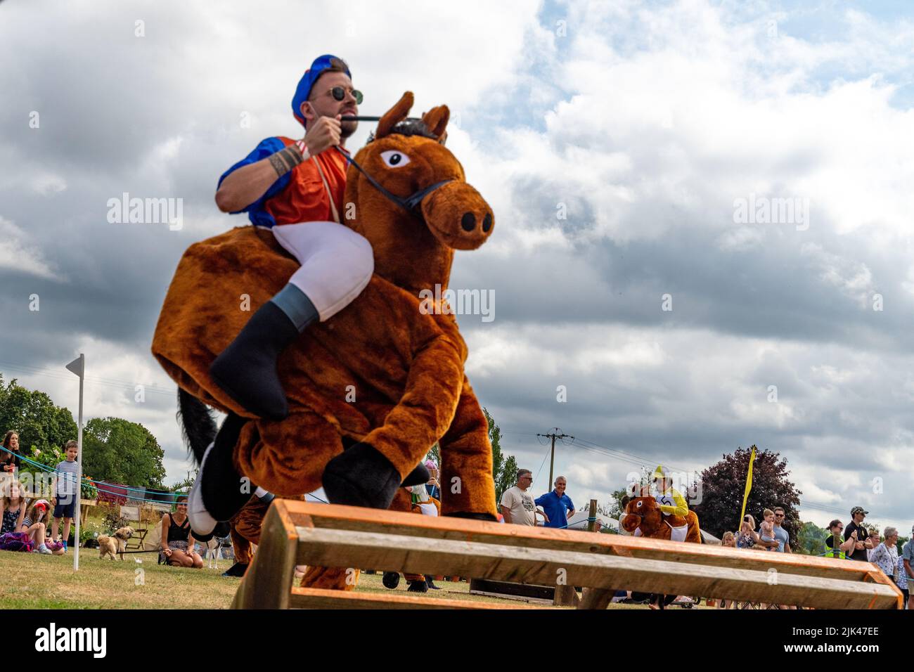 Damerham near Fordingbridge, Hampshire, UK, 30th July 2022. A horse and jockey jumping a fence in the Damerham Fair and Horticultural Show Damerham Derby fancy dress horse race. Paul Biggins/Alamy Live News Stock Photo