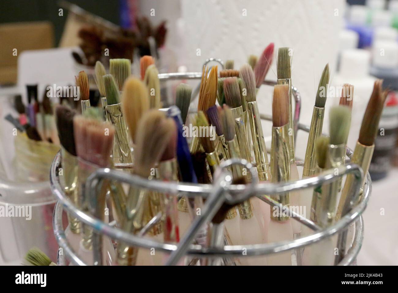 Artist paintbrushes stand ready for use with other art supplies in a still life. Stock Photo