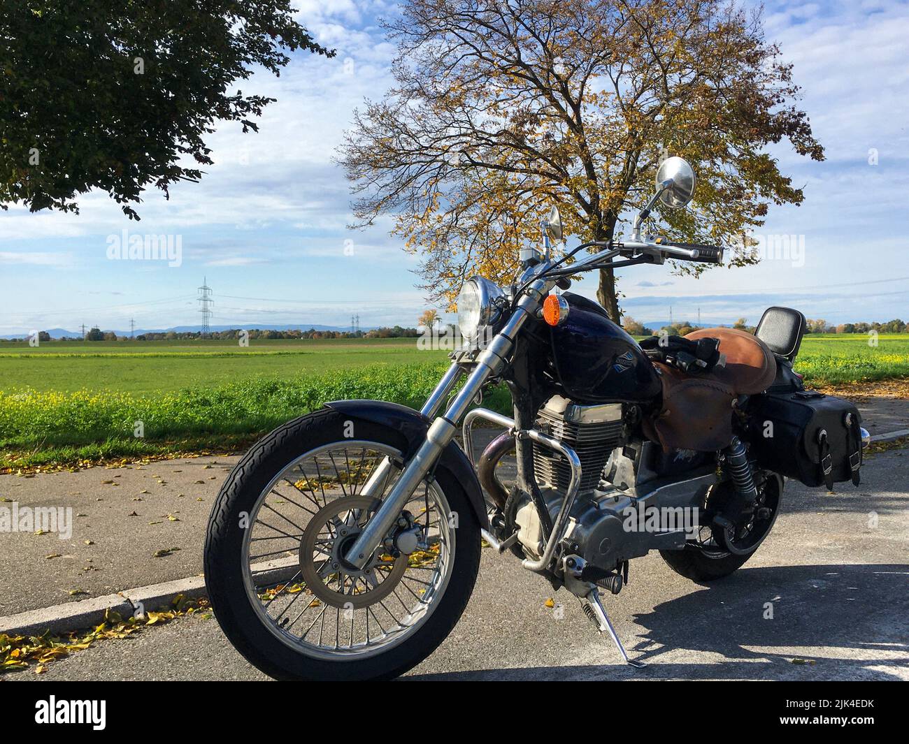 Chopper Motorrad steht am Straßenrand, im Hintergrund ein Feld Stock Photo