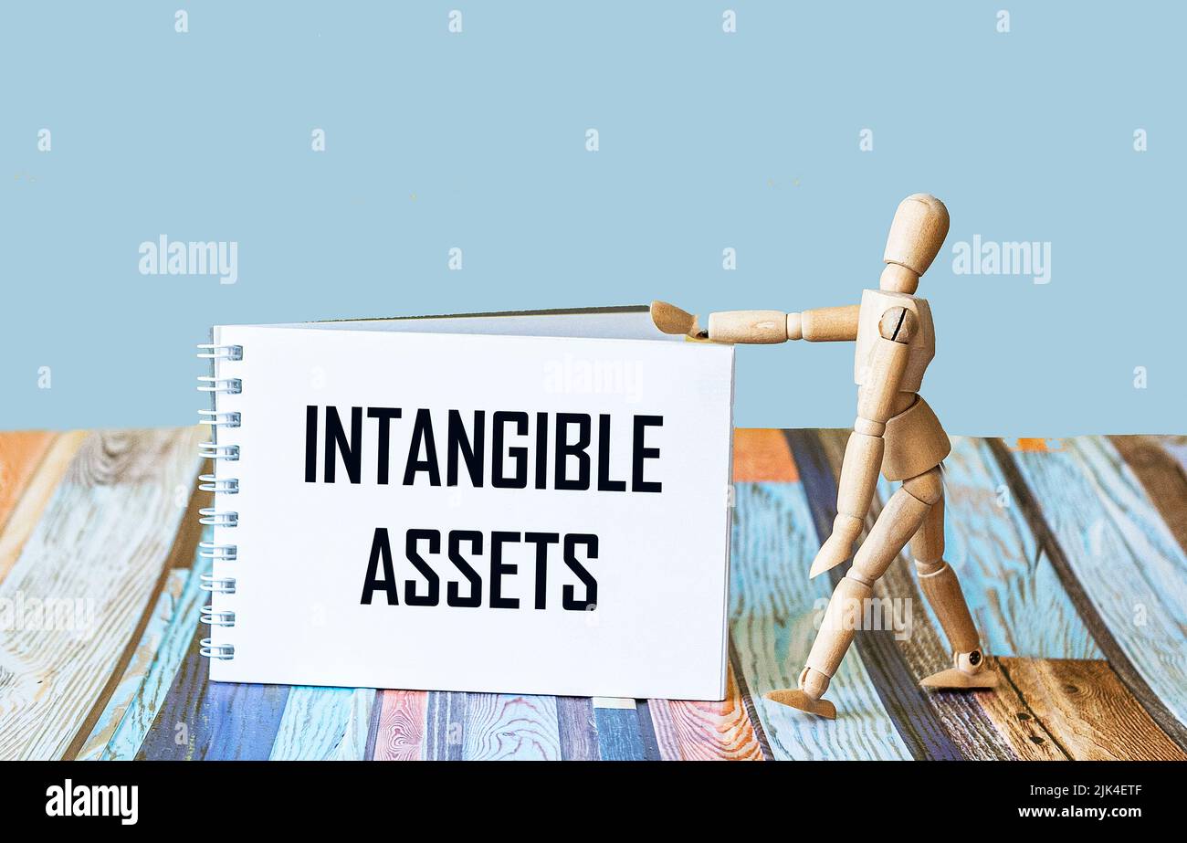 Intangible asset text written on a notepad, next to a wooden doll Stock ...