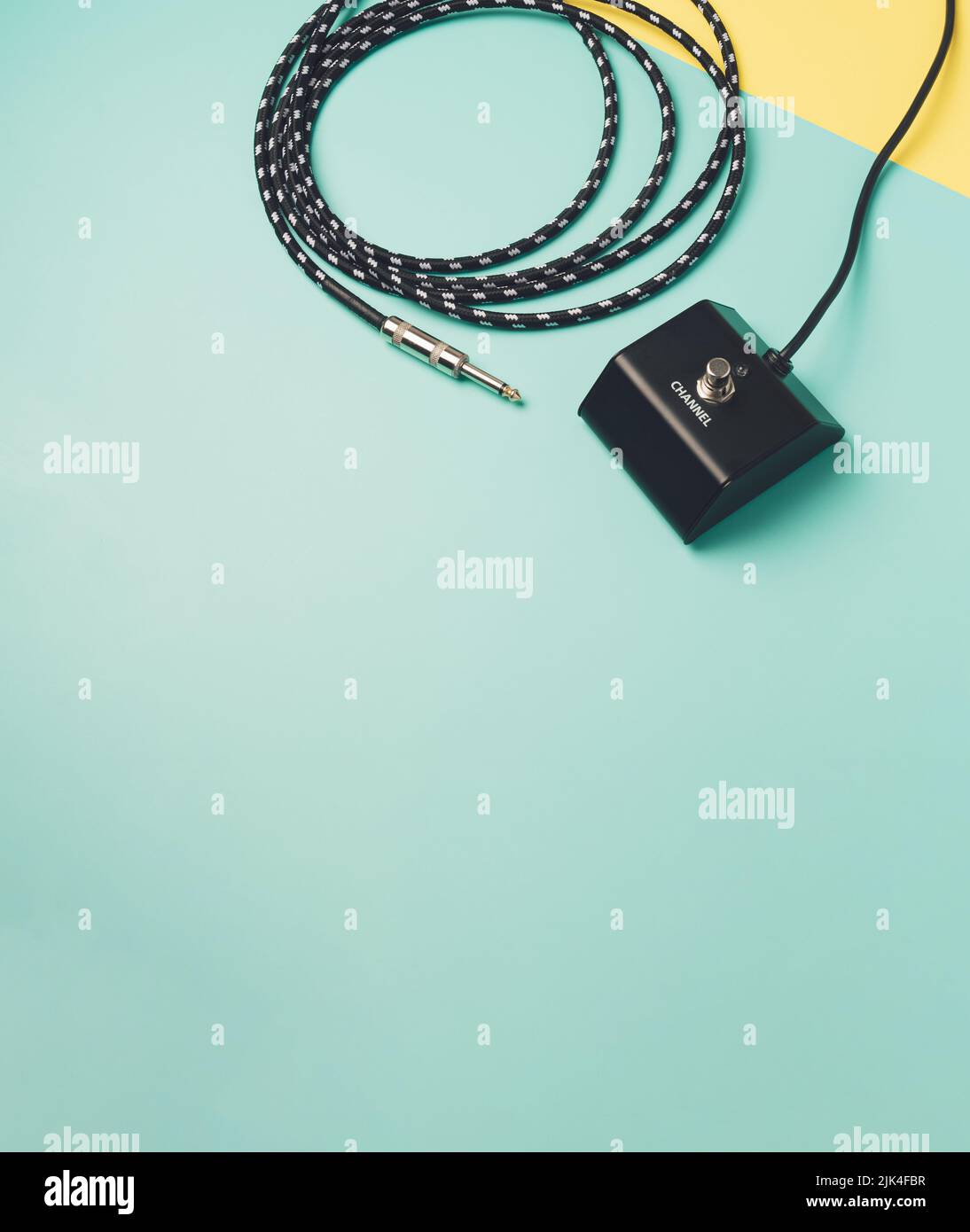 Electric guitar amp pedal with cable on a two tone pastel background. Concert equipment minimal