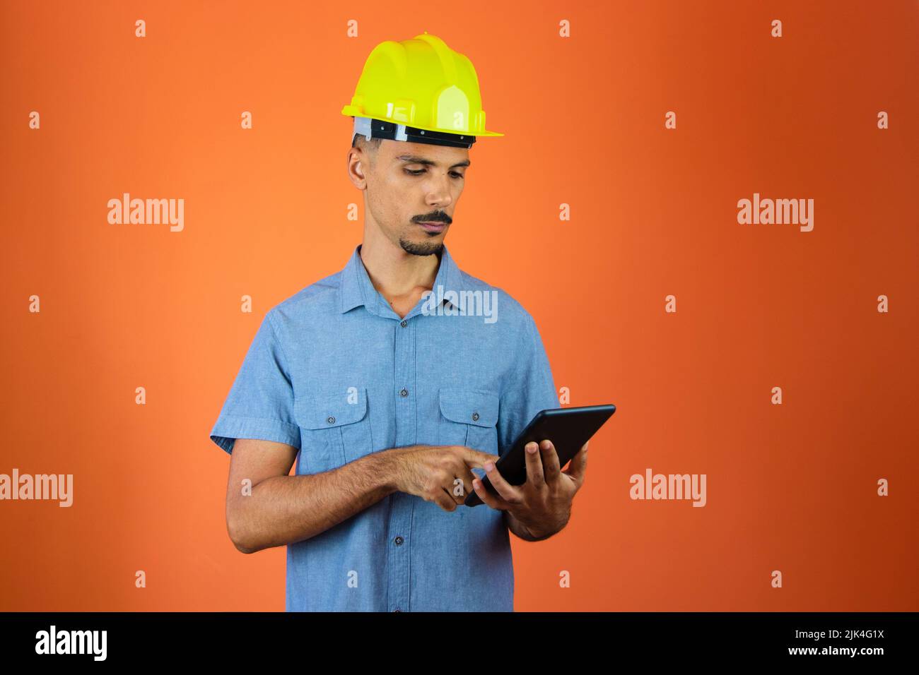 Engineer Holding Mobile isolated on Orange. Stock Photo