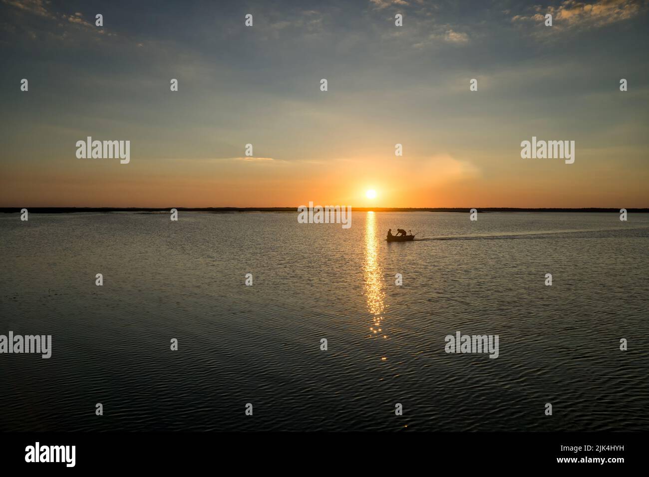 Fishermen are returning from fishing on Lake Lebsko at sunset. Cloudless sky, summer, light is reflected in the water. Pomerania, Poland, Europe. Stock Photo