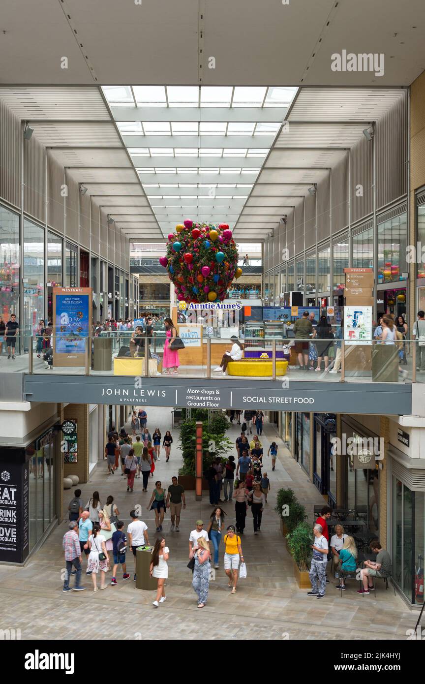 Interior of Westgate Shopping Centre with people walking past retail shops, Oxford, UK Stock Photo