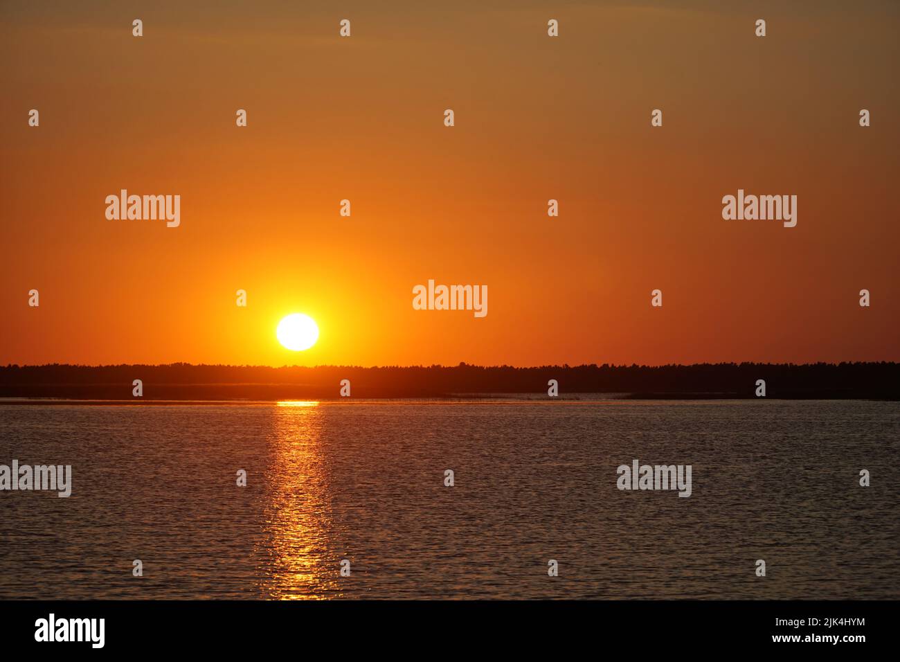 Sunset over the Lebsko lake, Pomeranian Voivodeship, Poland. Summer evening, clear sky, reflection of light in the water. Stock Photo