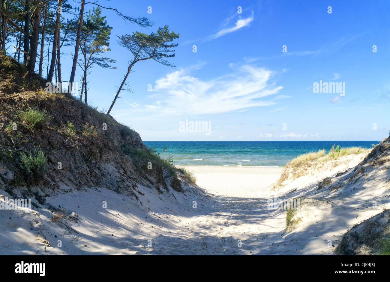 Entrance to a sandy beach through dunes, Baltic Sea near Łeba, Poland, Europe. Summer, little waves on the water, blue sky with white clouds. Stock Photo