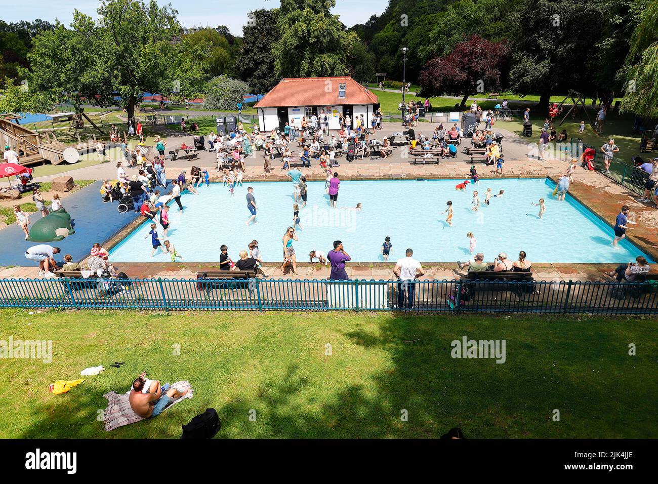 Families enjoying the hot weather by cooling down in the paddling pool