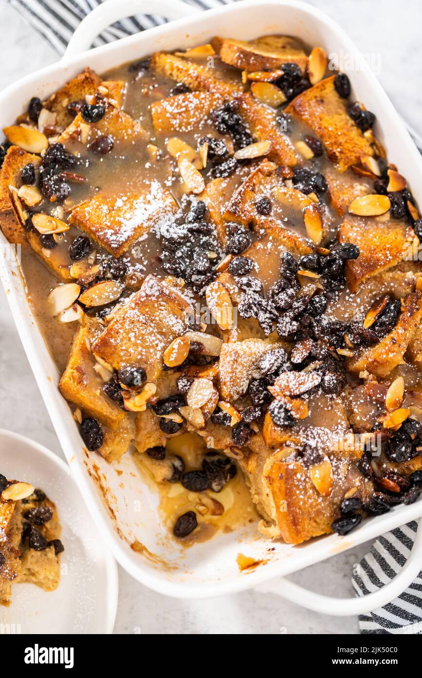 Serving freshly baked bread pudding with raising and almond slivers in