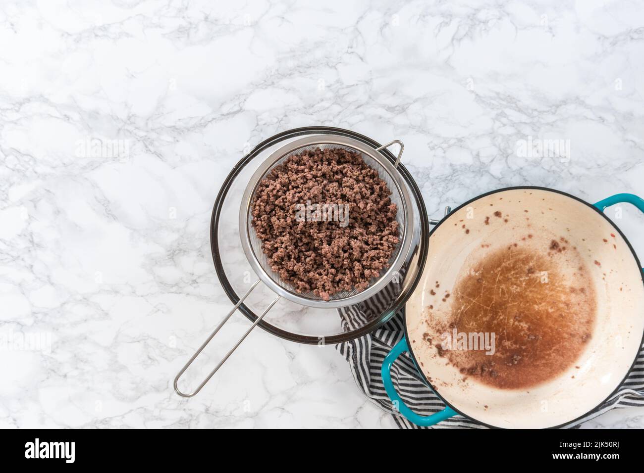 Flat lay. Draining brown ground beef meshed strainer to make homemade