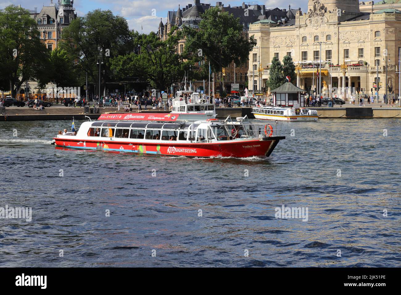 Stockholm, Sweden - July 29, 2022: Red Sightseeing boat at Nybroviken withe Royal playhouse in the background. Stock Photo