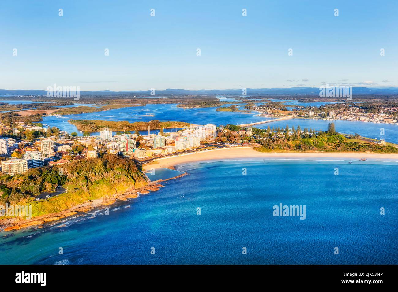 Main Forster beach on Pacific coast of Forster town in Australia - scenic aerial view to downtown from open sea and Wallis lake with bridge. Stock Photo