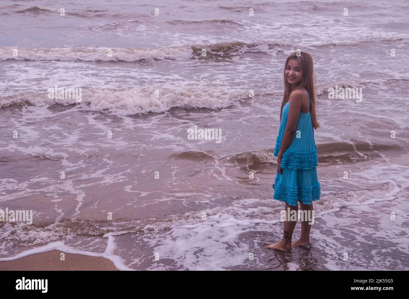 Beautiful young Cambodian woman, a domestic tourist, w/ long hair wearing a blue dress on Kep Beach, Cambodia. © Kraig Lieb Stock Photo