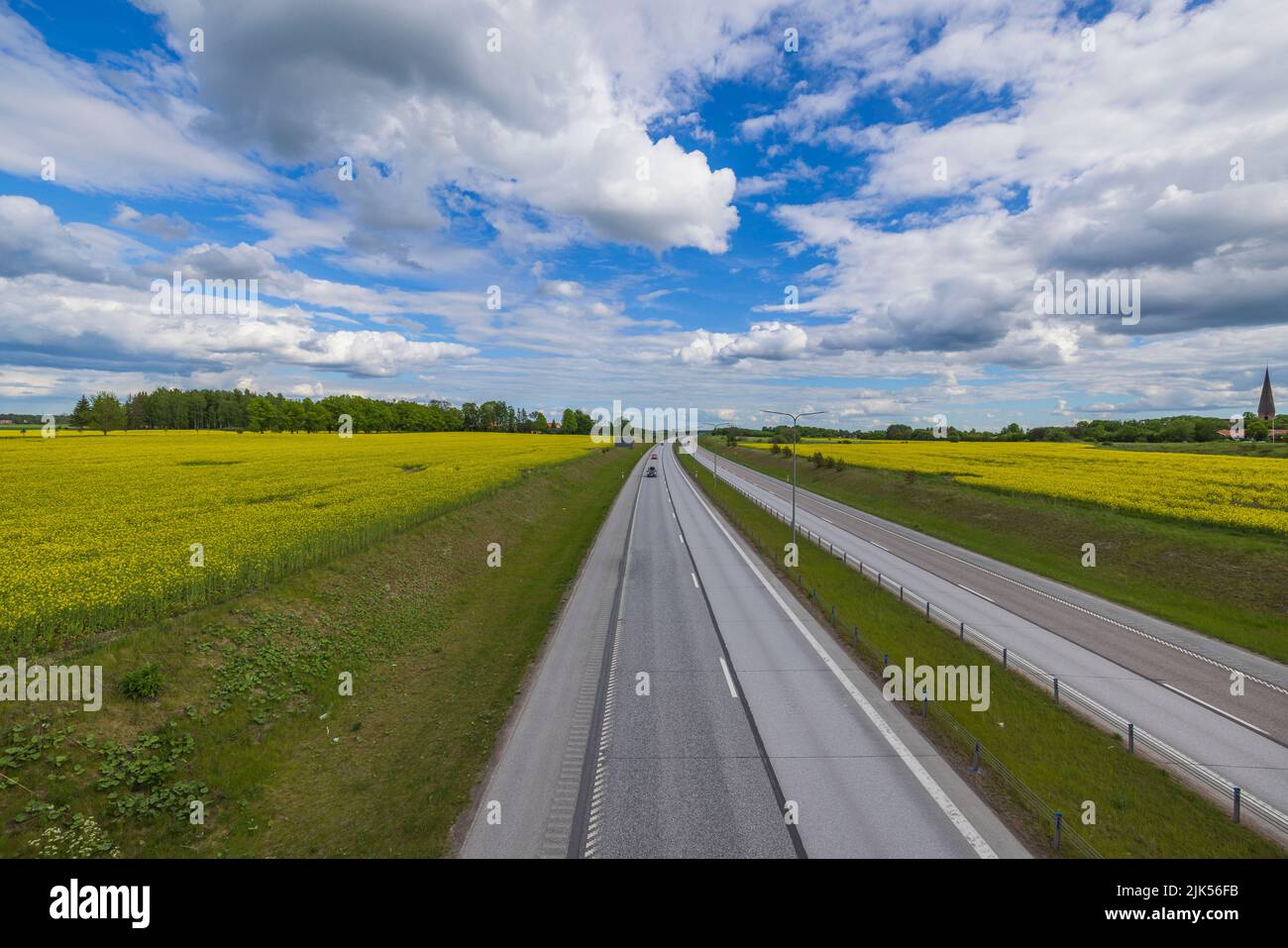 Beautiful top view of highway with several cars. Green side fields and clouds sky background. Sweden. Stock Photo