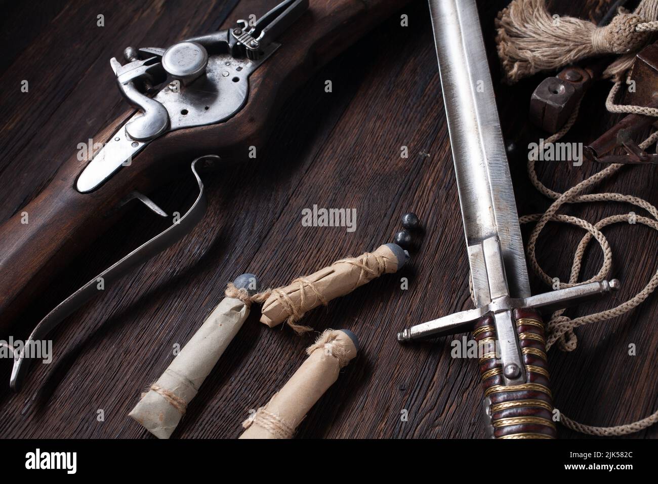 17th century ancient flintlock musket with powder flask and led bullets on wooden deck. Stock Photo