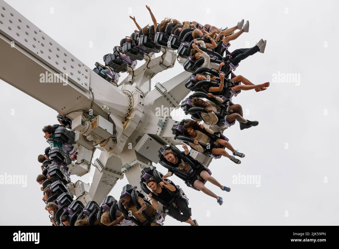 A pendulum ride with young people, legs dangling, arms in the air, smiling and excited Stock Photo