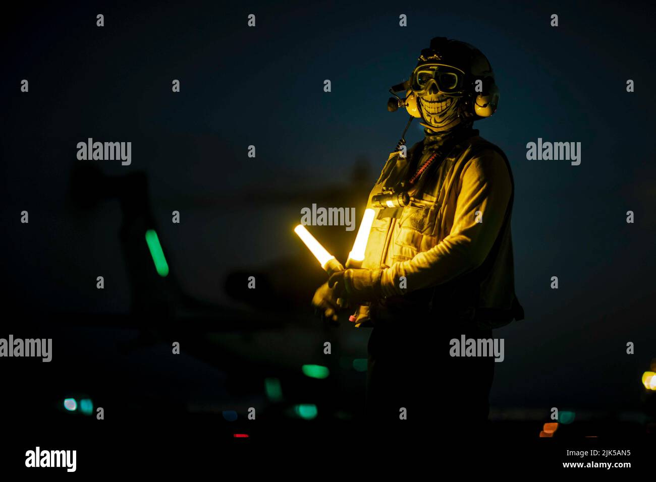 July 8, 2022 - Atlantic Ocean - Aviation Boatswain's Mate (Handling) 3rd Class Ronald Saunders prepares to direct an AH-1Z Viper helicopter, attached to the 22nd Marine Expeditionary Unit, on the flight deck of the Wasp-class amphibious assault ship USS Kearsarge (LHD 3) during night flight operations July 14, 2022. The Kearsarge Amphibious Ready Group and embarked 22nd Marine Expeditionary Unit, under the command and control of Task Force 61/2, is on a scheduled deployment in the U.S. Naval Forces Europe area of operations, employed by U.S. Sixth Fleet to defend U.S., allied and partner inter Stock Photo