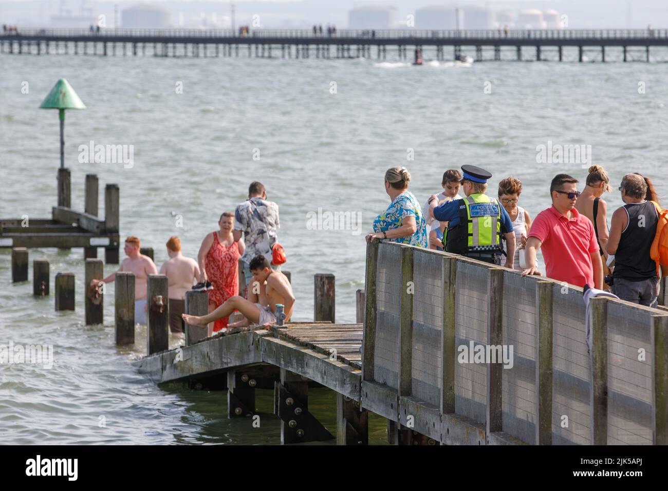 A Police community support officer tells people to get off a submerged pier on Southend beach during the UK heatwave of 2022 Stock Photo