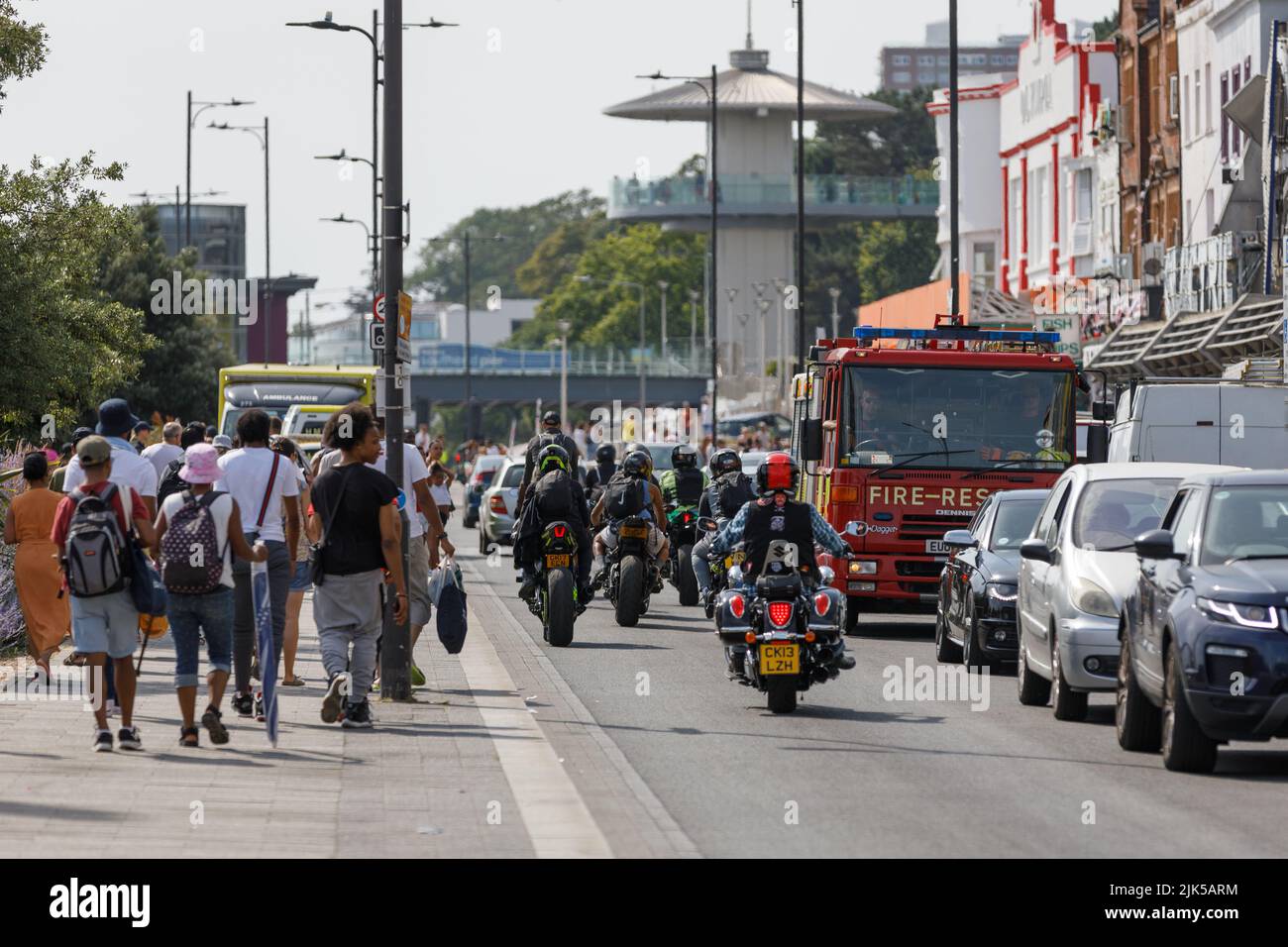 heatwave England. Traffic congestion with bikers, cars and fire engine on a busy road and pedestrians walking on a hot summer day in a English seaside Stock Photo