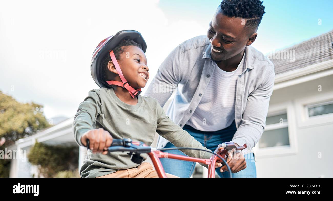 Sharing in some quality time while developing a new skill. a father teaching his son to ride a bicycle outdoors. Stock Photo