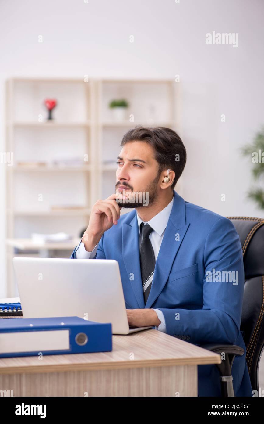 Deaf businessman employee using hearing aid in the office Stock Photo