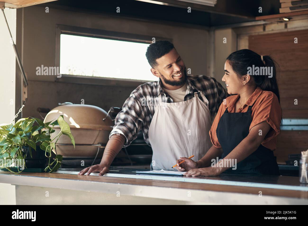 What toppings do you think we should put. two young restaurant owners standing inside together and planning their menu. Stock Photo