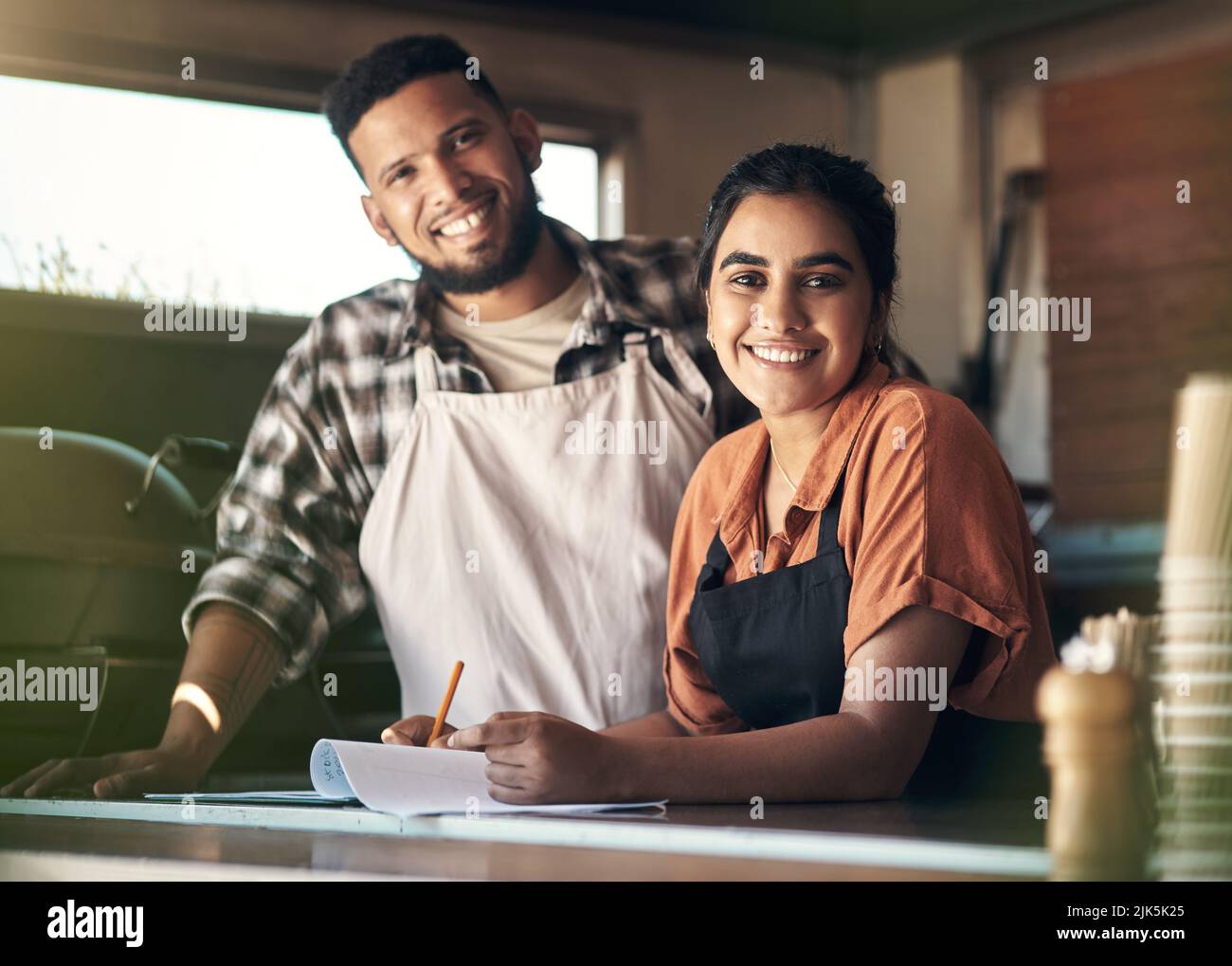 We built this from the ground up. two young restaurant owners standing inside together and planning their menu. Stock Photo