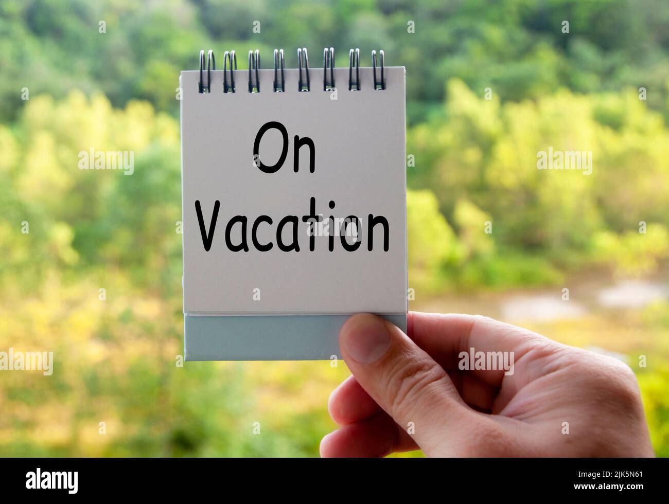 Hand holding notepad with text - On vacation. Vacation concept Stock Photo
