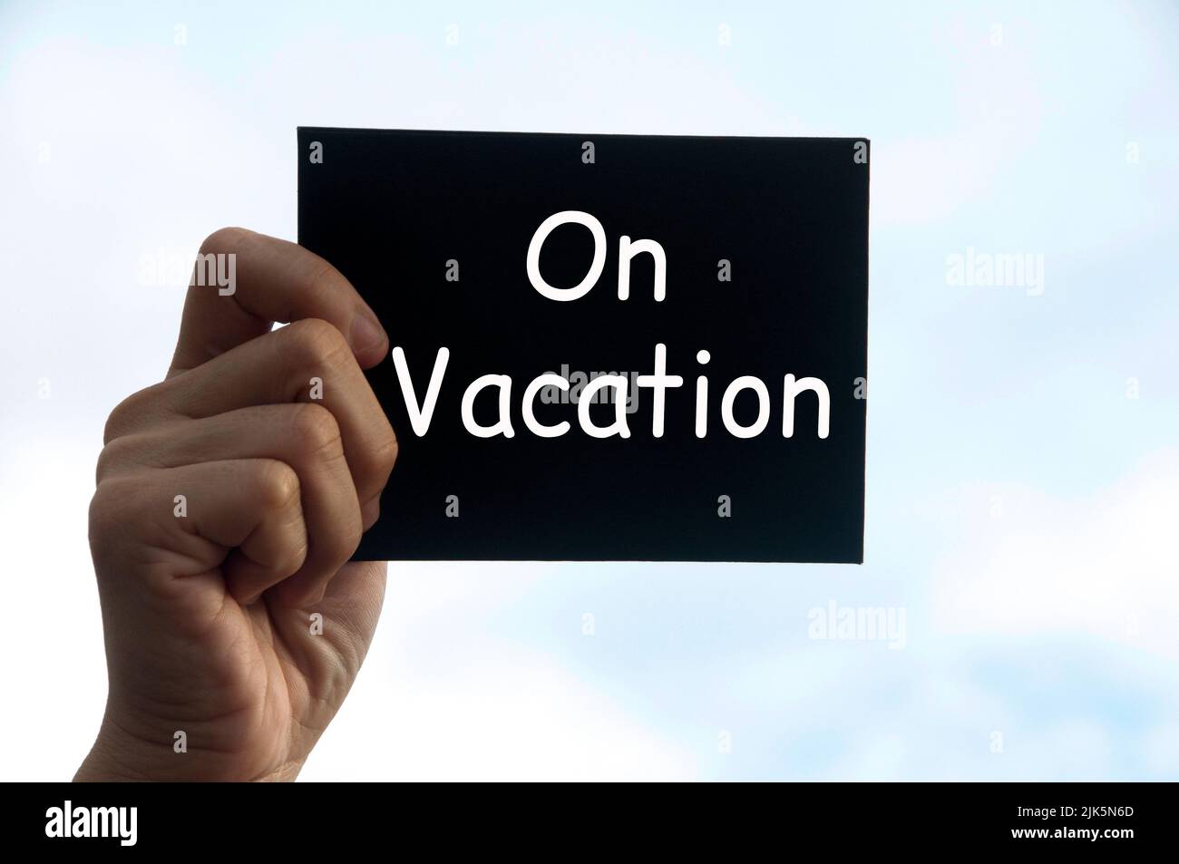 Hand holding black notepad with text - On vacation. Stock Photo