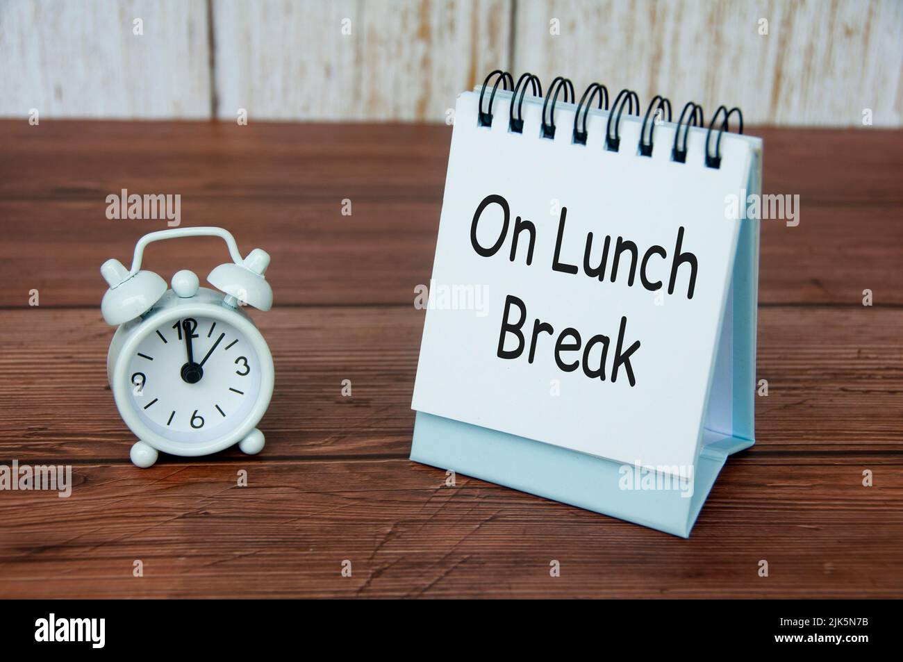 On lunch break text on white table calendar with alarm clock pointing at 12pm. Office concept Stock Photo