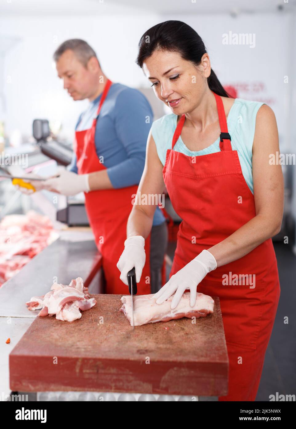 Happy female butcher cutting meat hires stock photography and images