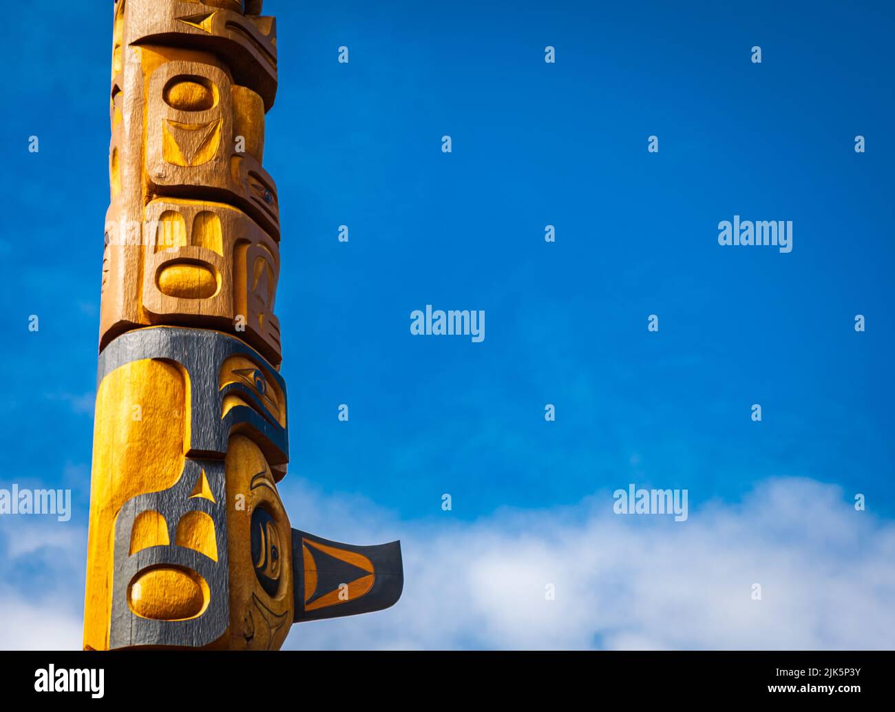 Isolated totem wood pole in blue sky background. Indian totem poles in park in Nanaimo, Canada. Travel photo, copy space for text, nobody Stock Photo