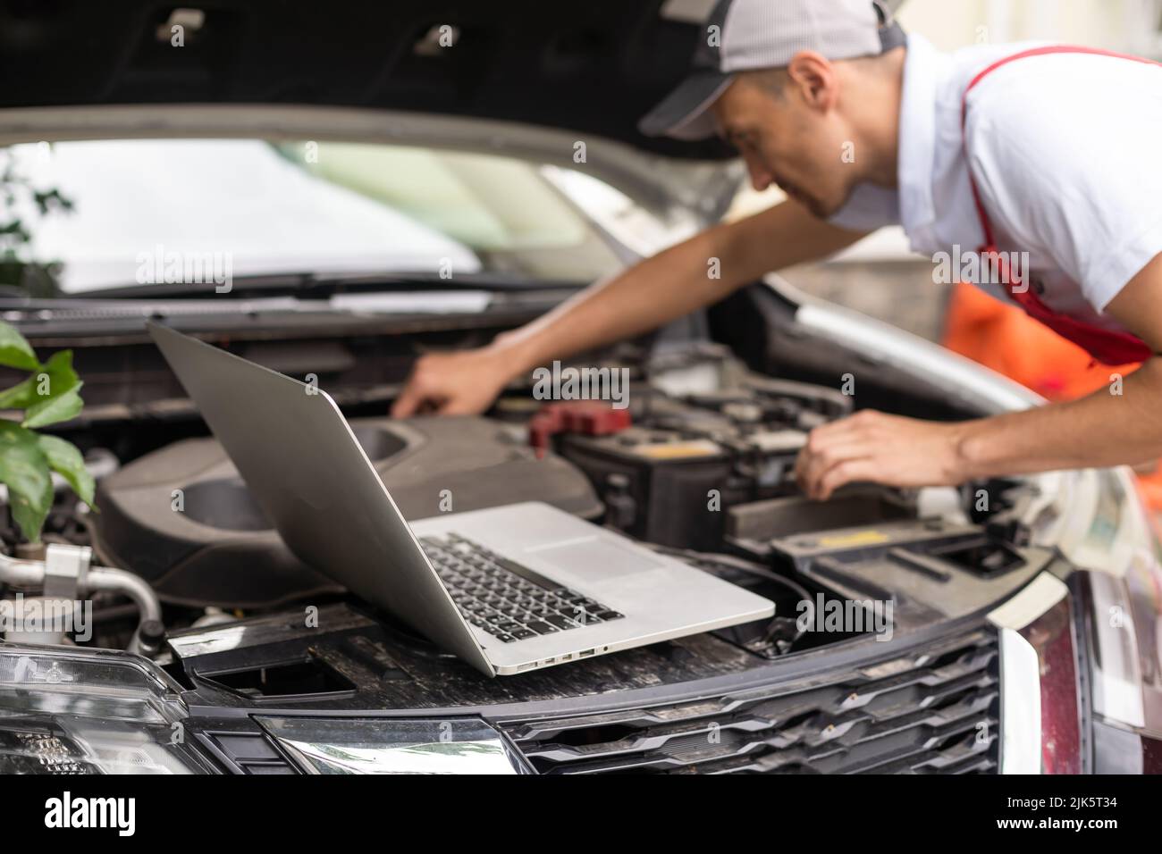 Mechanic with laptop near car engine. Modern car diagnostic program on