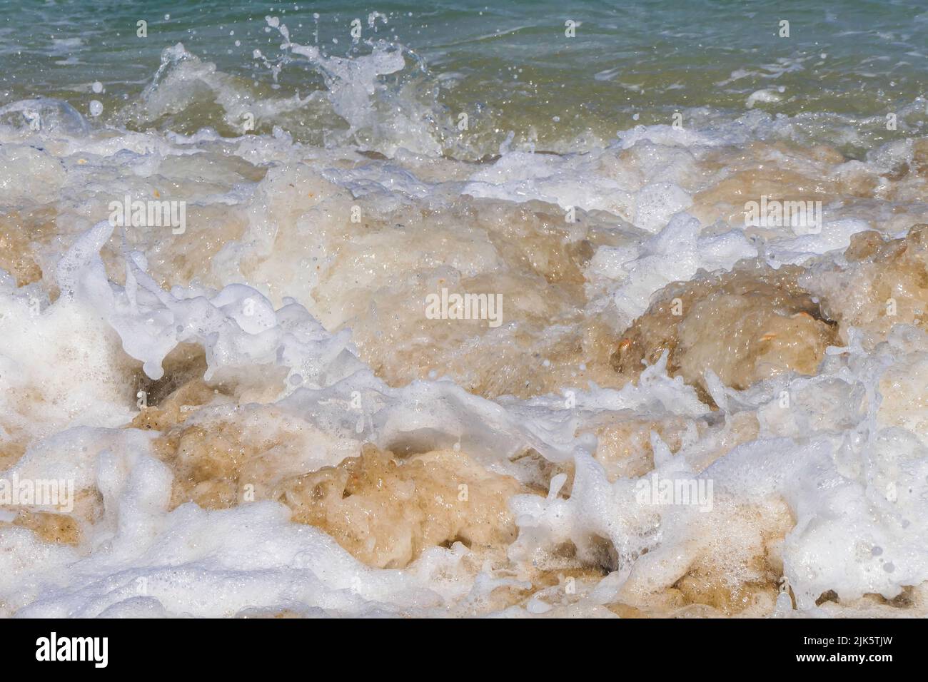 Foam and splashes on coastal waves. Sandy beach of the Mediterranean Sea. Stock Photo