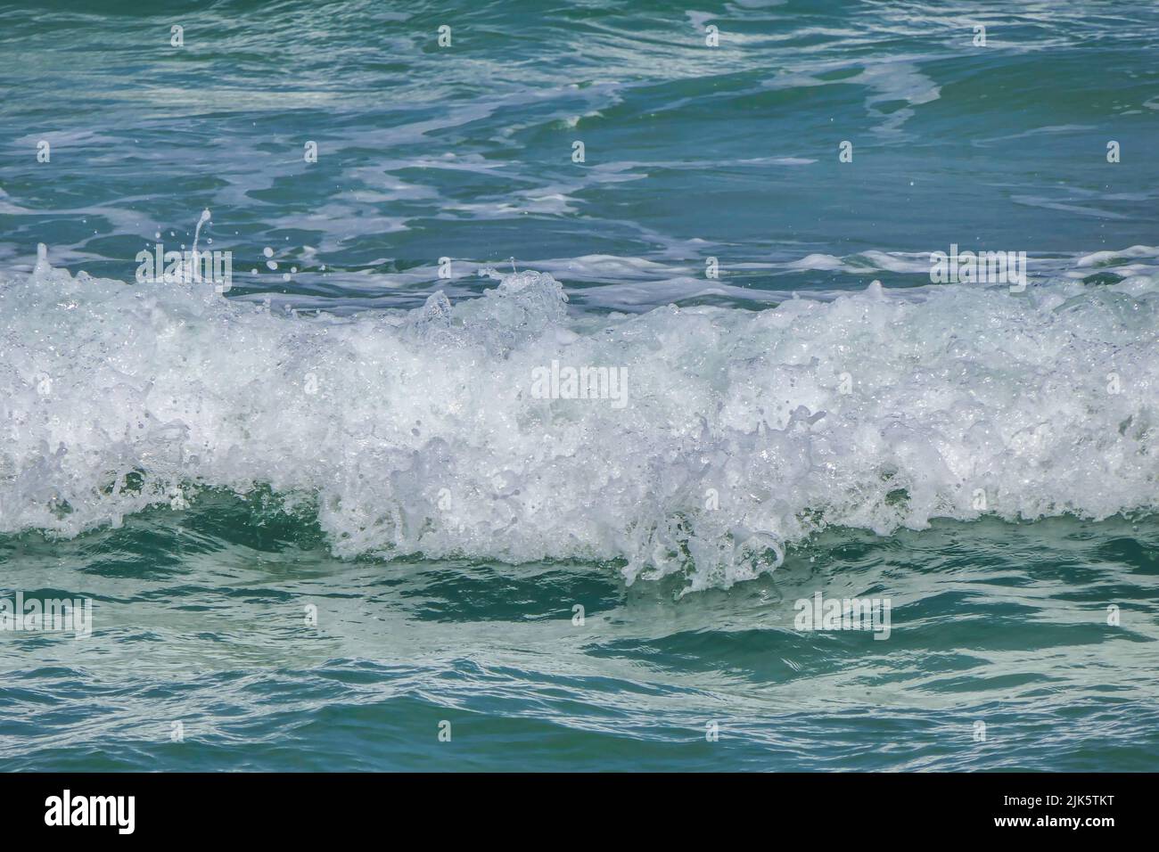 Foam and splashes on coastal waves. Sandy beach of the Mediterranean Sea. Stock Photo