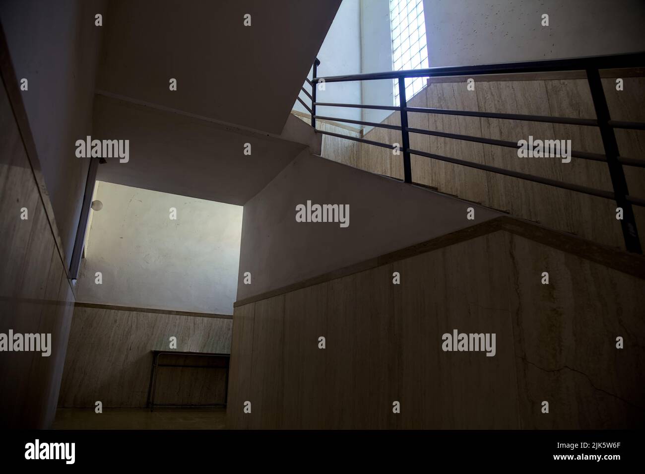 Staircase lit by a feeble light coming from a window Stock Photo