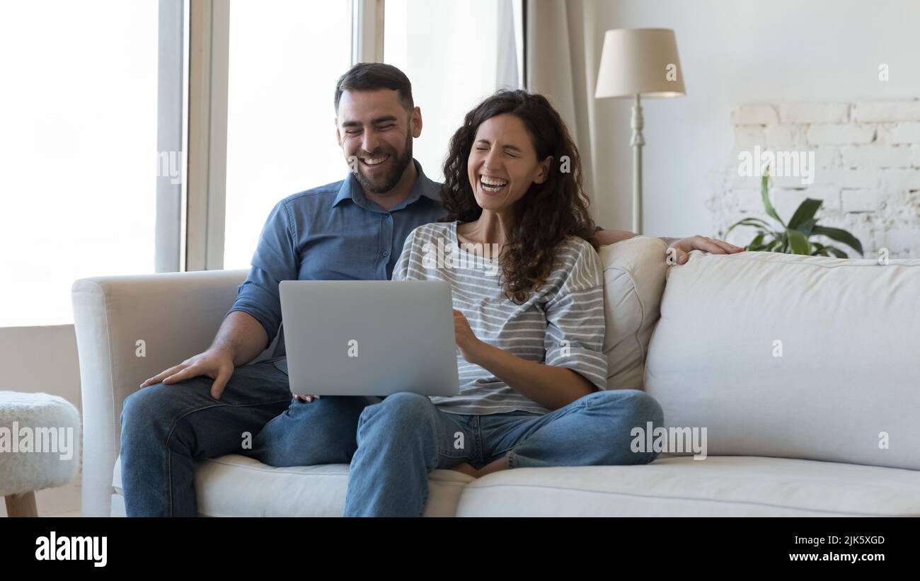 Happy overjoyed millennial couple using laptop at home together Stock Photo