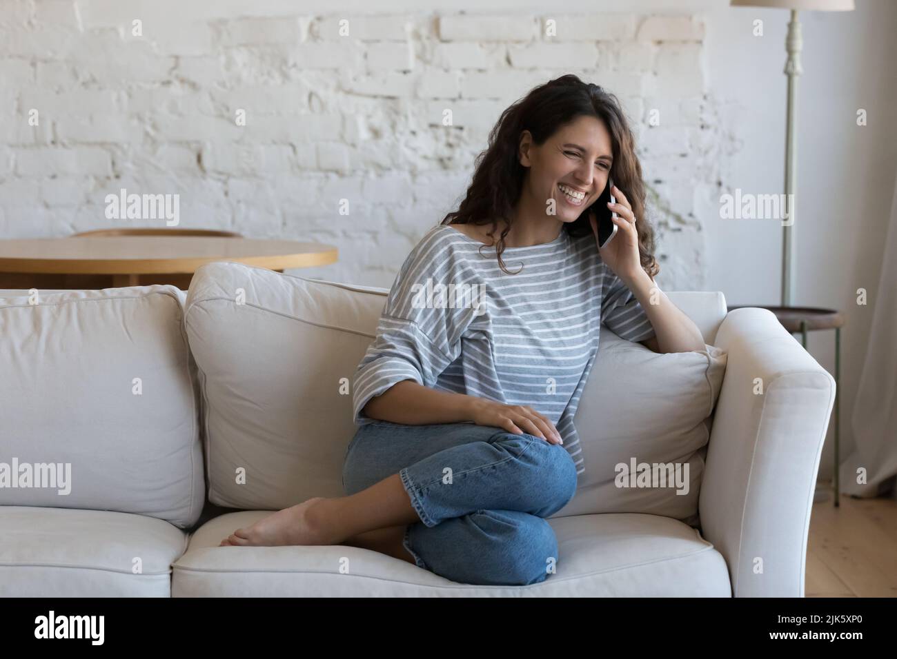 Joyful happy young adult Hispanic woman talking on cellphone Stock Photo