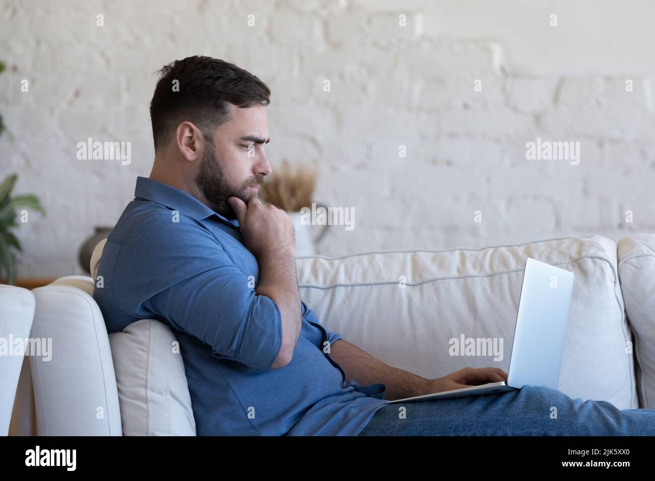 Serious pensive millennial freelance business man resting on sofa Stock Photo