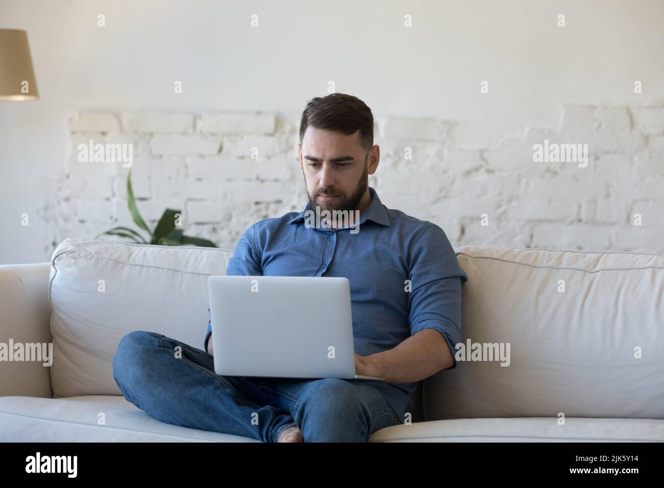 Serious freelance employee man using laptop computer Stock Photo - Alamy