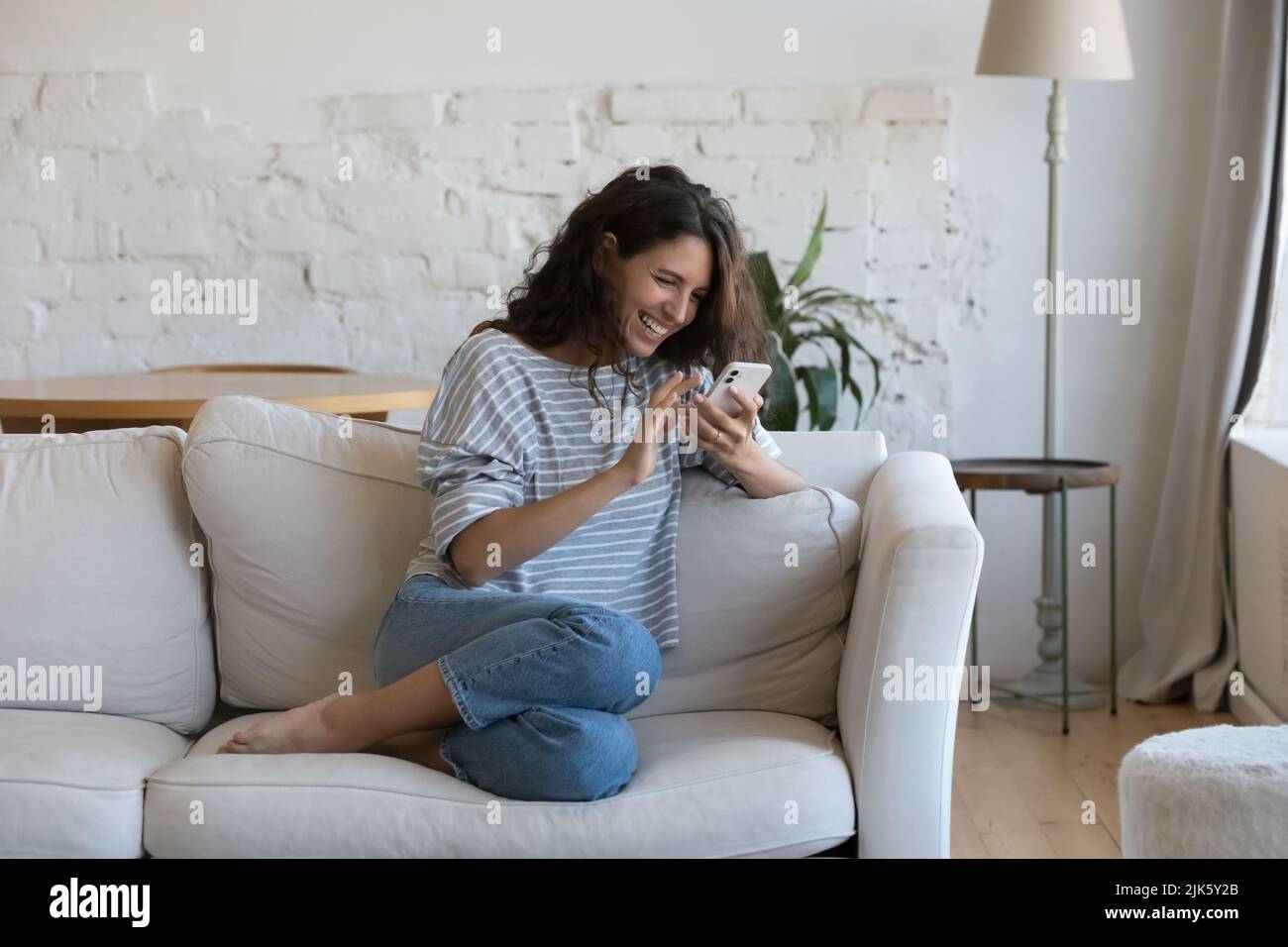 Excited happy young adult woman reading message on mobile phone Stock Photo