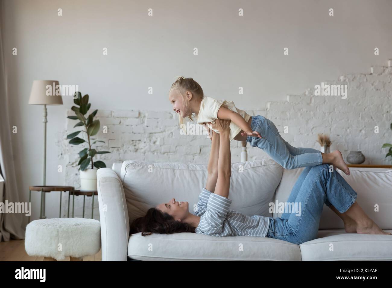 Happy mother holding excited kid on outstretched arms Stock Photo