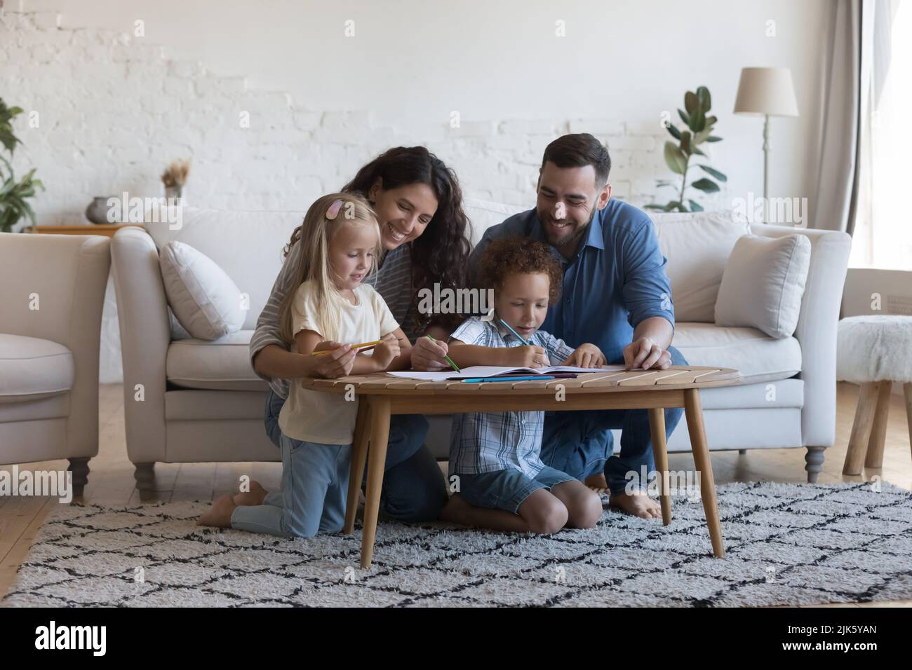 Mother and father helping children to draw in colored pencils Stock Photo