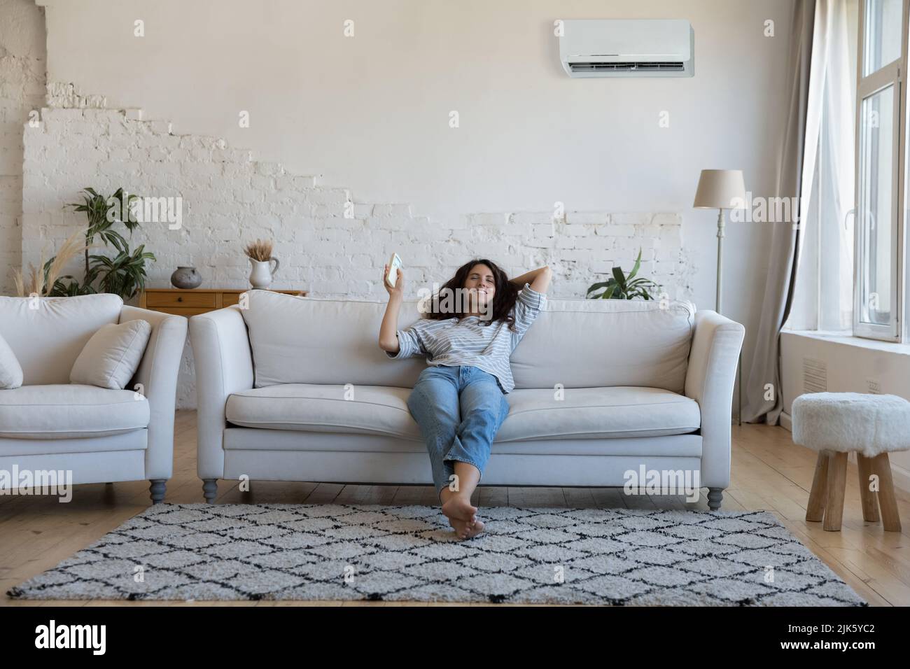 Happy pretty Latin woman enjoying cool conditioned air Stock Photo
