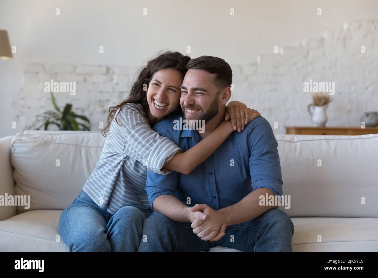 Happy joyful married couple in love sitting on couch Stock Photo